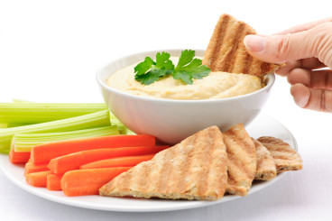 Photo of a hand dipping pita in hummus