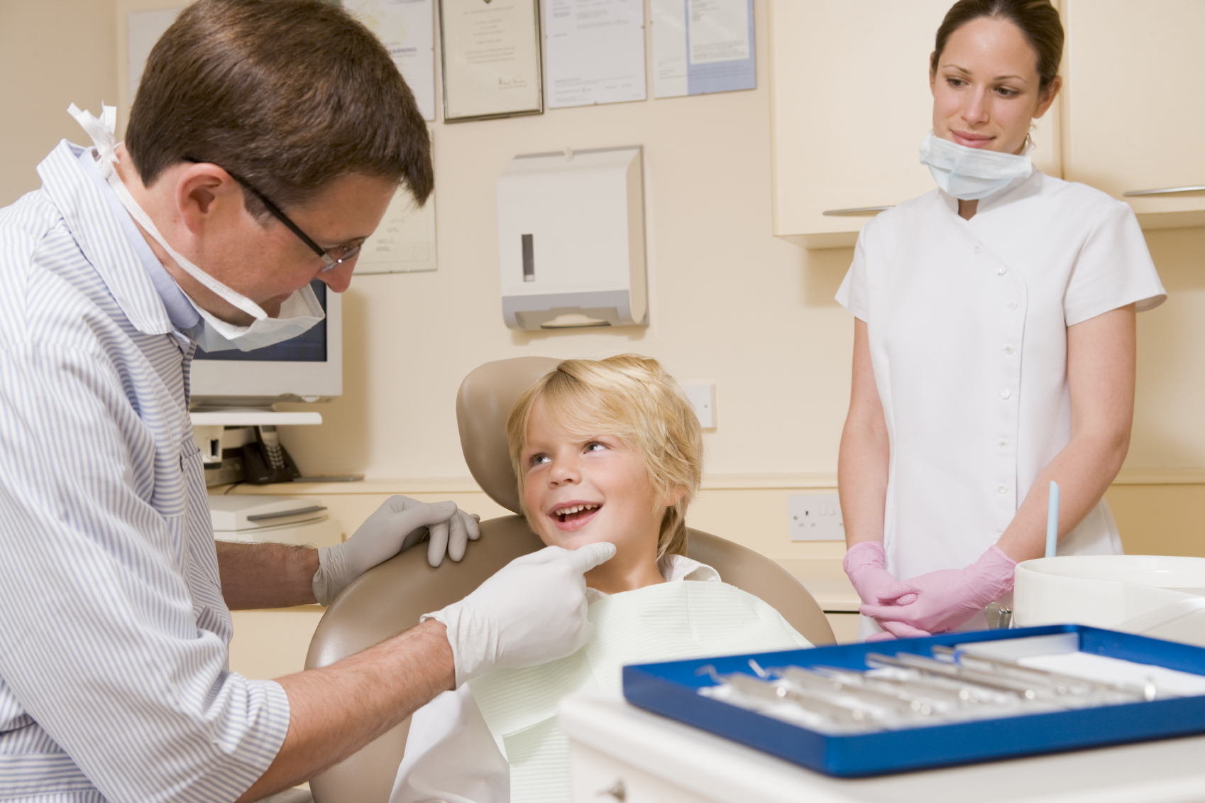 Dentist and assistant in exam room with young boy in chair