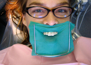 dental dam smiling teeth woman glasses dental office exam cleaning