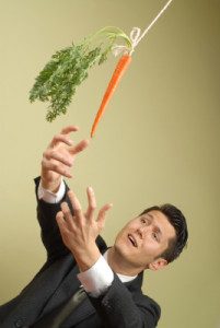 man in suit lunging for a carrot on a string