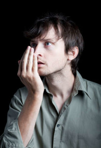 man smelling breath in his cupped hand