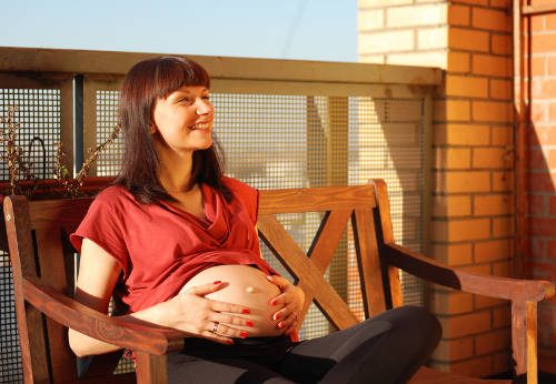 smiling pregnant woman on bench