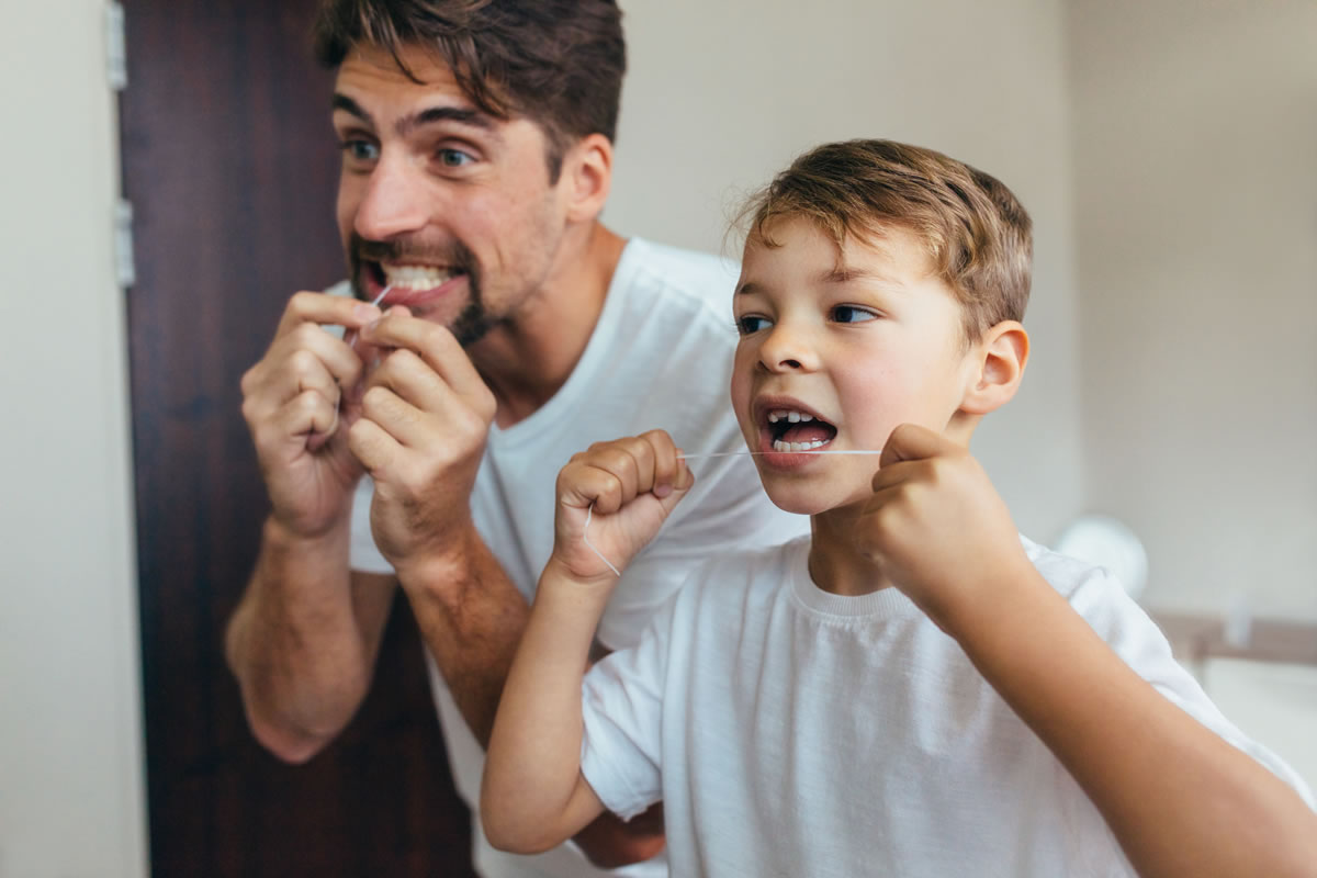 Father and son flossing teeth together.