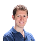 A man with short brown hair, wearing a blue polo shirt, smiling at the camera against a white background.