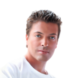 A person with short, styled hair and blue eyes, wearing a white shirt, is looking directly at the viewer against a plain white background.