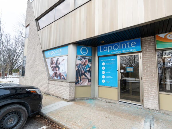 The image shows the exterior of a dental office with signage for Lapointe Dental Centres. There's a photograph of smiling people on the window and a parked car in front. The building's facade is modern, with large windows and beige paneling.