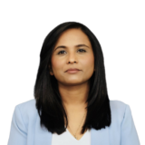 A person with long dark hair in a light blue blazer against a plain white background.