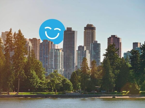 A city skyline with tall skyscrapers and lush green trees by a calm water body, featuring a large blue smiling face in the sky.
