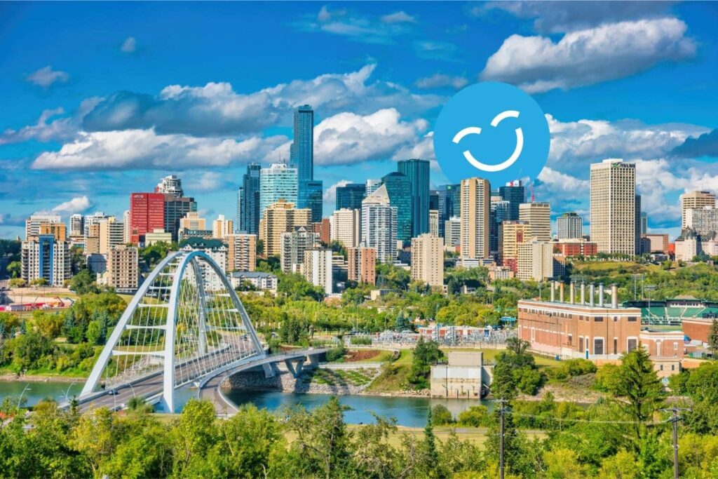 City skyline with modern skyscrapers, a white bridge, and lush greenery under a blue sky with clouds and a smiling face icon.