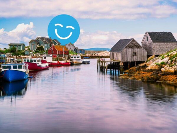 A serene coastal scene featuring colorful fishing boats docked by weathered wooden huts along a calm waterway, under a cloudy sky. A cheerful blue smiley face overlays the image.