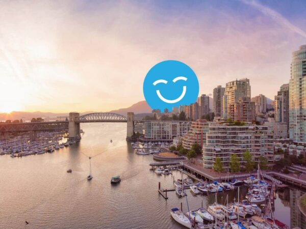 Sunset view of a city harbor with boats and skyscrapers, featuring a bridge in the background and a large smiling face icon in the sky.
