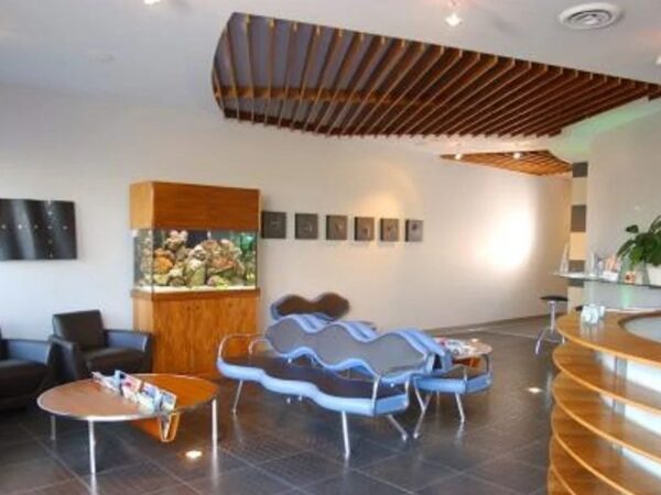 A modern reception area featuring stylish furniture, an aquarium, and decorative plants. The space is well-lit with wooden accents and art on the walls, creating a welcoming atmosphere for visitors.