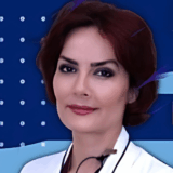 A confident woman with short, dark red hair and a white lab coat smiles gently against a blue background with abstract shapes, exuding professionalism and warmth.