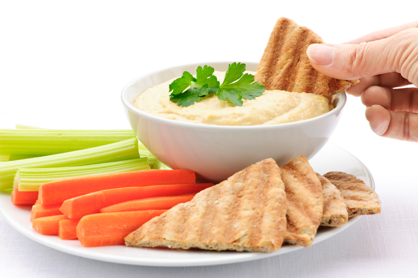 Photo of a hand dipping pita in hummus