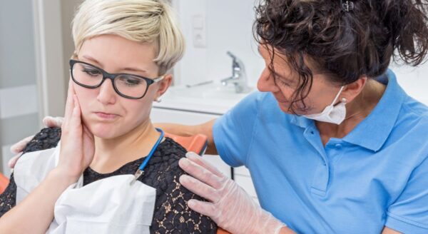 Dentiste calmant un patient dans le fauteuil dentaire