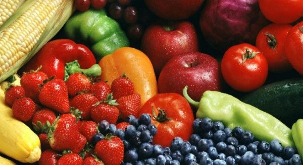 A colorful assortment of fresh fruits and vegetables, including apples, tomatoes, strawberries, blueberries, corn, and various peppers. The vibrant display highlights a variety of shapes and colors, emphasizing healthy, organic produce.