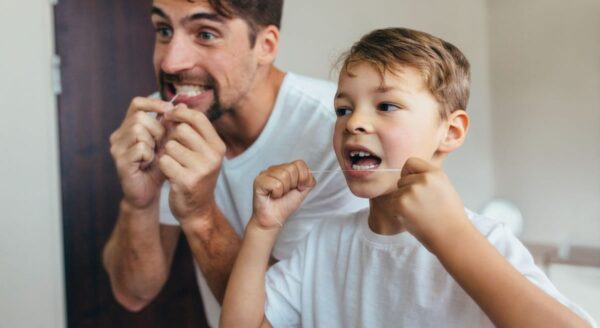 Father and son flossing teeth together.