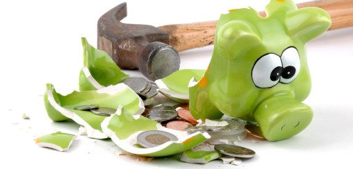 A broken green piggy bank lies shattered on a surface, surrounded by scattered coins and smoothed fragments. A hammer rests nearby, suggesting it was used to break open the bank.