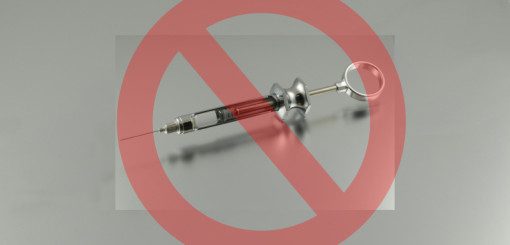 A syringe with red liquid, overlaid with a red circle and diagonal line, indicating a prohibition or warning against its use.