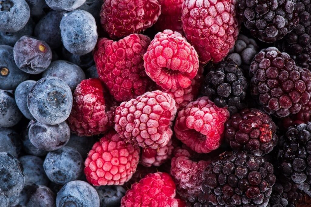 A close-up image of an assortment of fresh, frosty berries, including blueberries, raspberries, and blackberries, showcasing their vibrant colors and textures. Perfect for a healthy snack or dessert option.