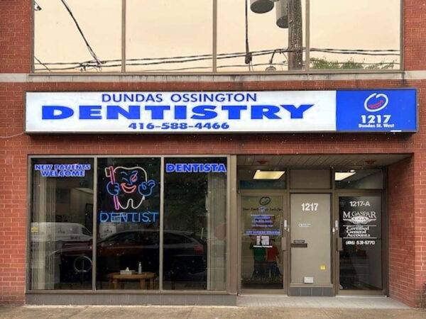 Exterior view of Dundas Ossington Dentistry, featuring a prominent sign with the practice's name and contact number. The storefront includes a dental-themed neon sign and large windows, displaying the office interior.