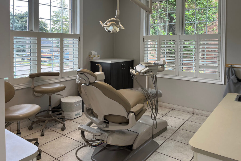 A dental office featuring a comfortable examination chair, dental tools, and bright windows that provide natural light. The space is clean and inviting, ideal for patient comfort.