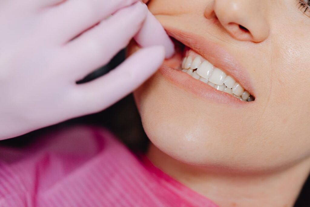 A close-up of a person's mouth as a dentist in pink gloves examines their teeth. The image highlights dental care and hygiene during a check-up.