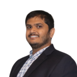 A person in a formal suit with a slight smile against a plain white background.