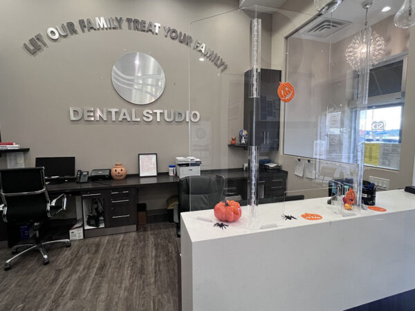 Modern dental office with a clean design, featuring a reception desk adorned with small pumpkins, a comforting slogan on the wall, sleek dark cabinets, and a welcoming atmosphere.