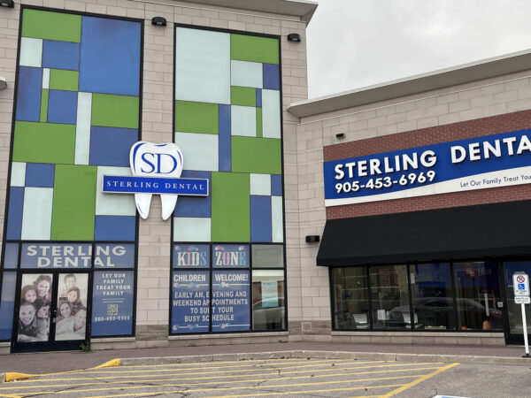 The exterior of Sterling Dental features colorful geometric patterns and prominent signage, with contact information displayed above the entrance.