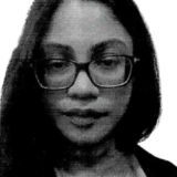 A person with long hair and glasses, wearing a neutral expression, is seen in a close-up portrait.