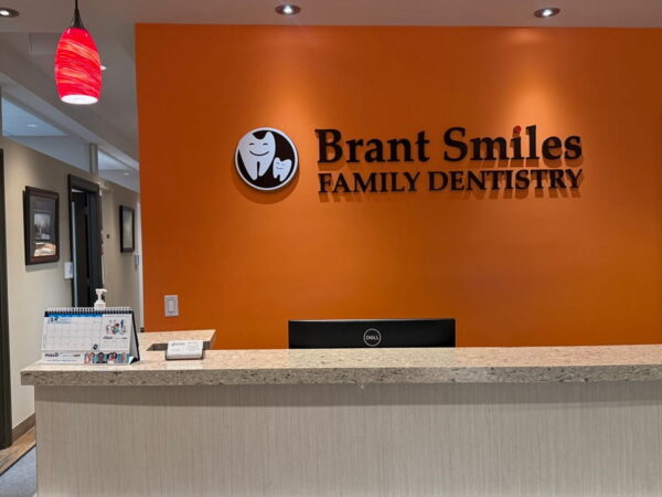 Reception area of Brant Smiles Family Dentistry with an orange wall, a counter, and warm lighting.