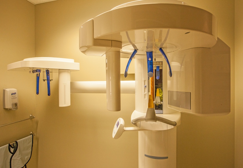 Dental imaging equipment in a warmly lit room, featuring a modern panoramic X-ray machine with blue and white details.