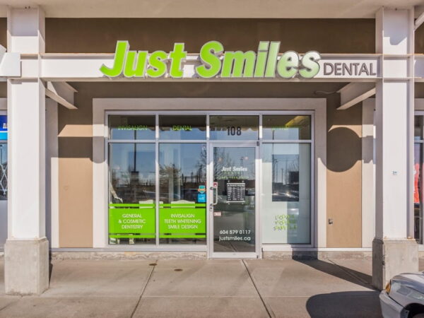 Front view of Just Smiles Dental clinic with glass doors and bright green signage.
